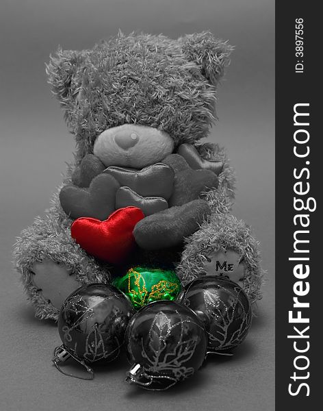 A teddy bear holding hearts in his hands, one highlighted red, with one green ball in front. A teddy bear holding hearts in his hands, one highlighted red, with one green ball in front.