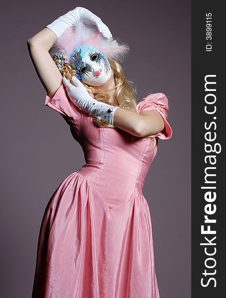 Blonde woman in mask and pink dress. Blonde woman in mask and pink dress