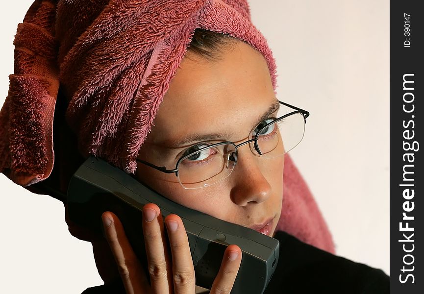 A young female with a towel on her head talking on the phone. A young female with a towel on her head talking on the phone