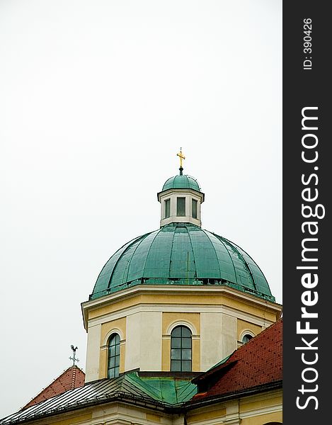 Roofs of church and house with weather vain and cross steeple