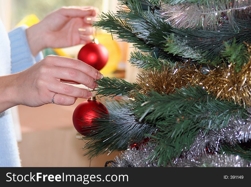 Hands hanging red baubles on christmas tree. Hands hanging red baubles on christmas tree