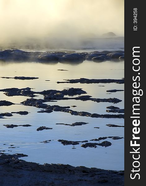 Mist and rocks of the Great Fountain Geyser in Yellowstone National Park, Wyoming lit by sunset light. Mist and rocks of the Great Fountain Geyser in Yellowstone National Park, Wyoming lit by sunset light