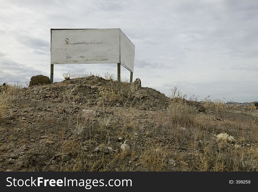 Blank wood double-faced sign in desert overlooking highway. Blank wood double-faced sign in desert overlooking highway.