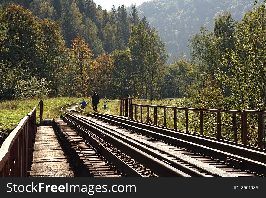 Father and son walks along the railway to see the mountains. Father and son walks along the railway to see the mountains