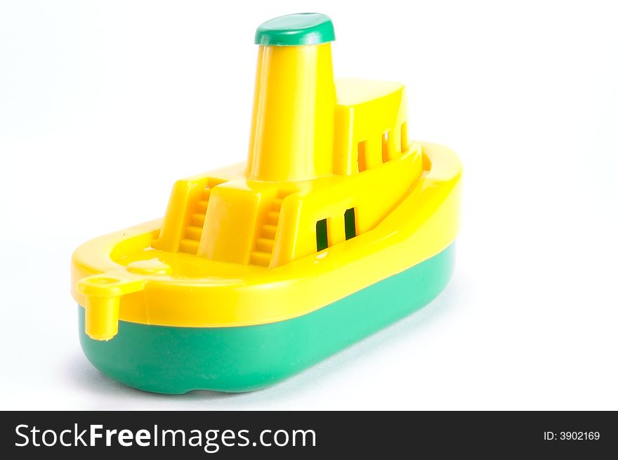 Plastic toy ship. On a white background. Top-yellow. Bottom - green.