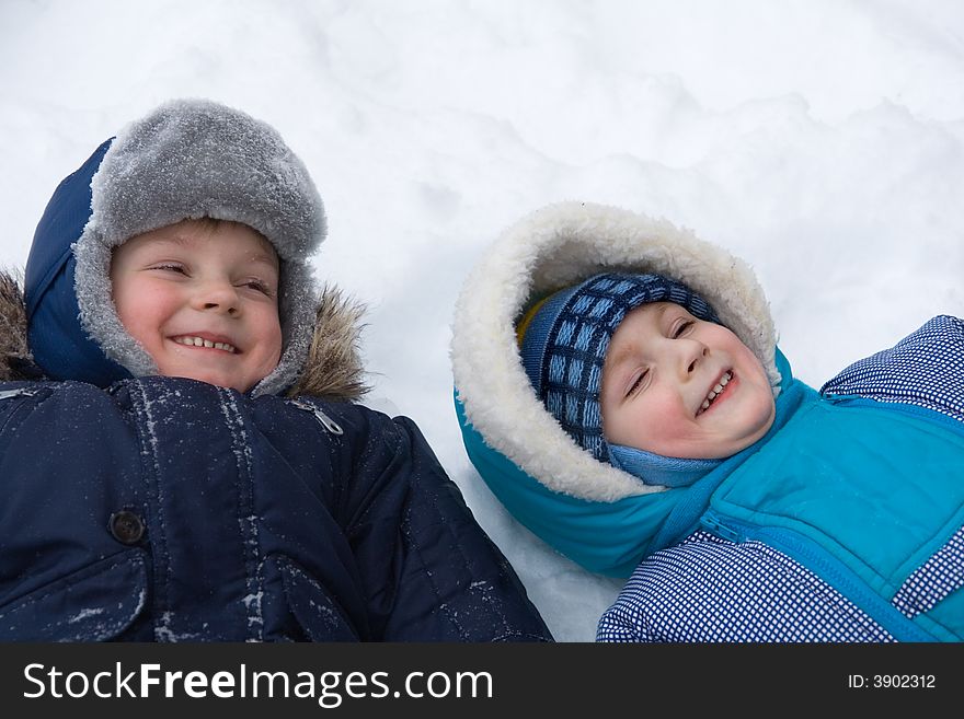 Two cheerful boys lay on a snow. Two cheerful boys lay on a snow
