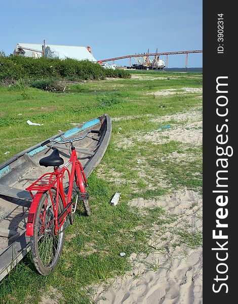 Red bicycle and canoe in the dry bed of the river Tapajos in the dry period, with the terminal boarding of soybeans to fund - City of Santarem - Brazil