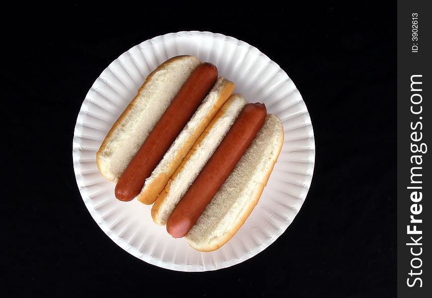 A pair of hot dogs on a paper plate. A pair of hot dogs on a paper plate.