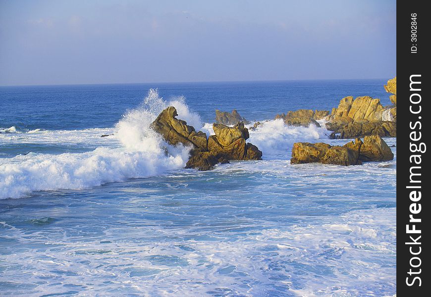 Ocean water splashing against jagged rocks. Ocean water splashing against jagged rocks.