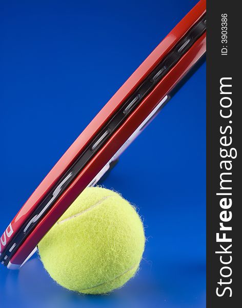 Tennis ball is next to a part of a tennis racket