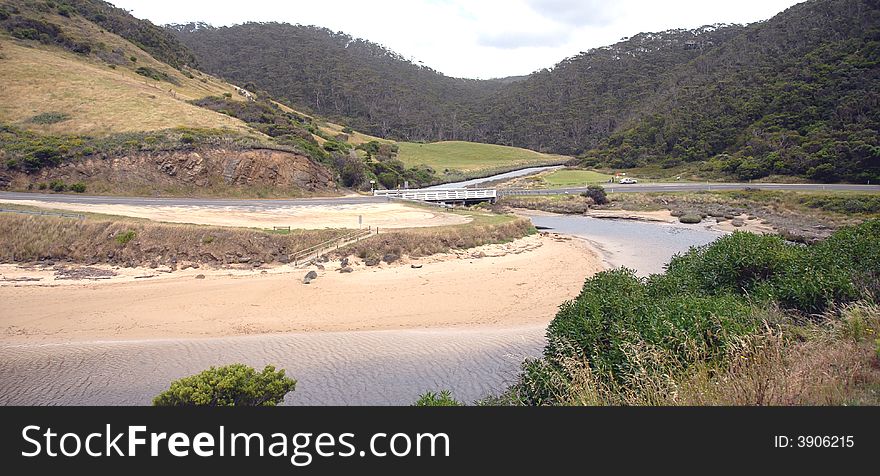 Bridge over small river leading to sea and with green background. Bridge over small river leading to sea and with green background