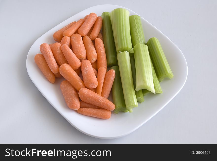 Baby carrots and celery stalk on a plate.