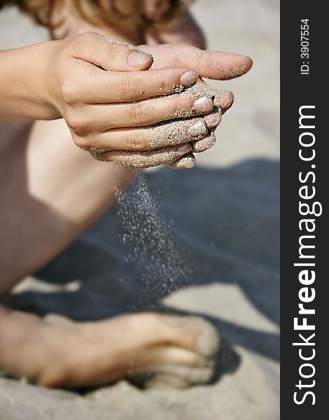 Sand dropping down through girl's fingers