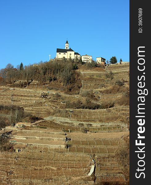 Church on a hill covered with vineyards in Segonzano, Italy. Winter period. Church on a hill covered with vineyards in Segonzano, Italy. Winter period