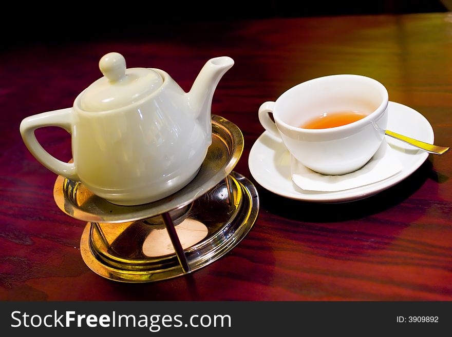 Set of teapot and cup in warm cafe light. Set of teapot and cup in warm cafe light