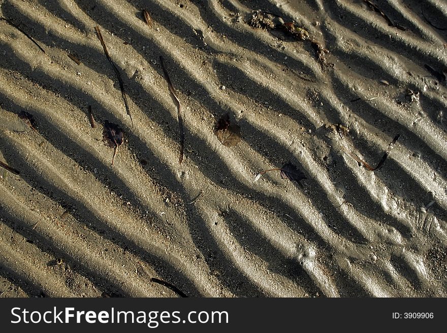 Small wave ripples in the wet sand at low tide . Background. Small wave ripples in the wet sand at low tide . Background