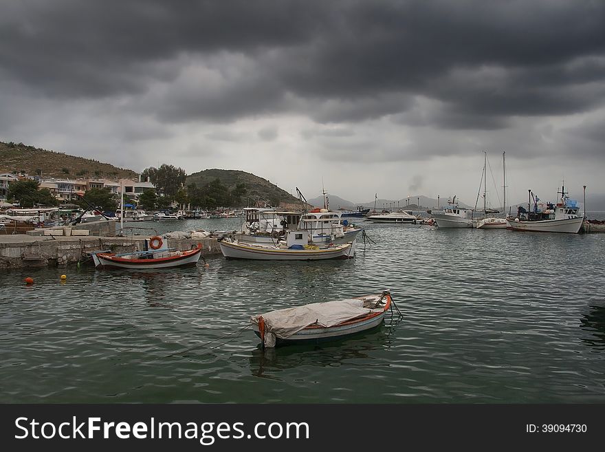 A view of a quiet fishing harbor in foggy morning with the seagulls above.Pachi village 45 km from Athens,Greece. A view of a quiet fishing harbor in foggy morning with the seagulls above.Pachi village 45 km from Athens,Greece