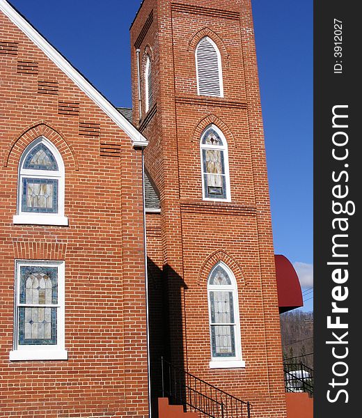 An Arched stained glass window in a brick church with great architectural design. An Arched stained glass window in a brick church with great architectural design.