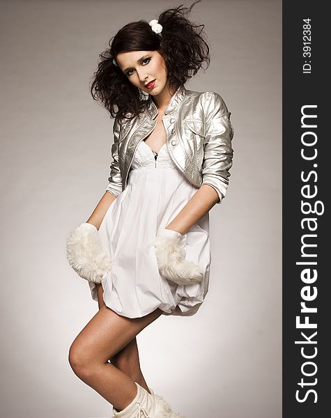 Beautiful brunette winter girl wearing furry gloves and boots on light background