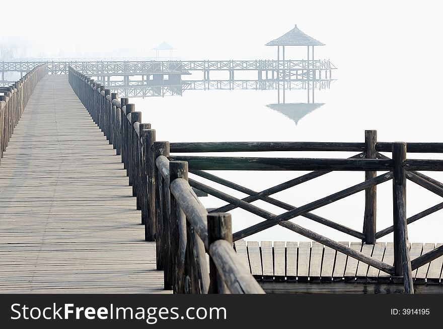 Chinese style pavilion and wooden bridge in fog