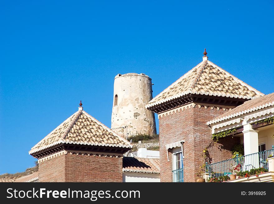 Front building towers with spanish defensive tower in background. Front towers covered in andalusian style. Front building towers with spanish defensive tower in background. Front towers covered in andalusian style.