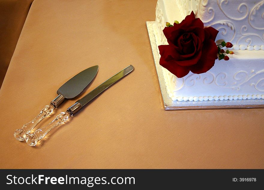 The wedding cake serving pieces lay close to the wedding cake. The wedding cake serving pieces lay close to the wedding cake.