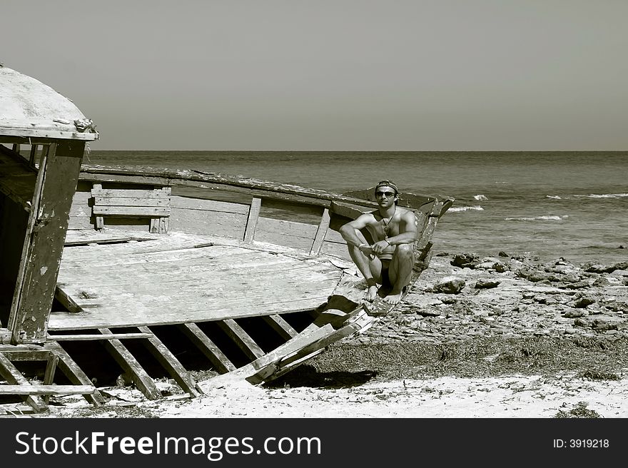 B/W portrait of a man sitting on the ship wreck on a beach. B/W portrait of a man sitting on the ship wreck on a beach.