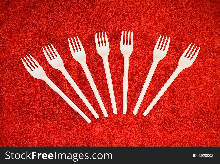 White plastic forks on red background