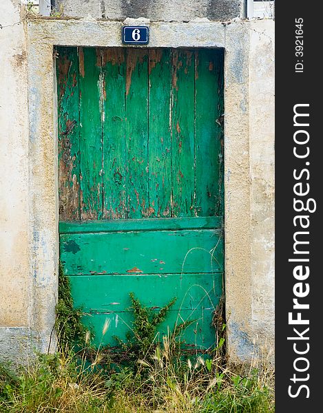 An old and dirty wooden door, green painted. It shows the effect of the time pass. An old and dirty wooden door, green painted. It shows the effect of the time pass