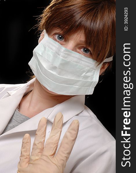 Attractive young lady doctor in white coat with face mask - on black background. Attractive young lady doctor in white coat with face mask - on black background