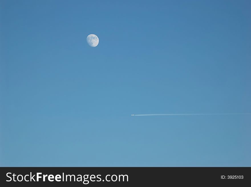 An aircraft is passing by the moon in the clear blue sky. An aircraft is passing by the moon in the clear blue sky.
