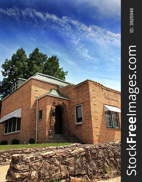 Brick house with stone wall and vivid blue sky.