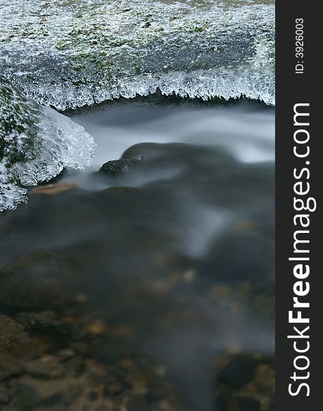 Motion blurred winter stream with detail of frozen stones