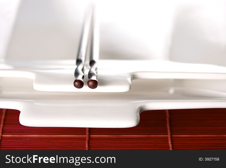 Wooden Chopsticks & White Plate on Bamboo Placemat