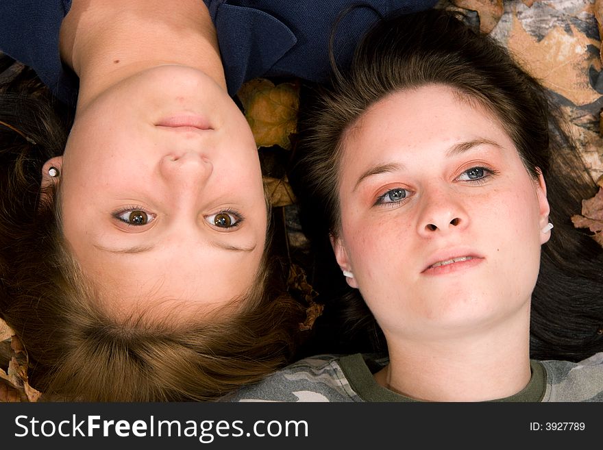 Two teenage girls lying on leaves with dreamy gaze upwards. Two teenage girls lying on leaves with dreamy gaze upwards