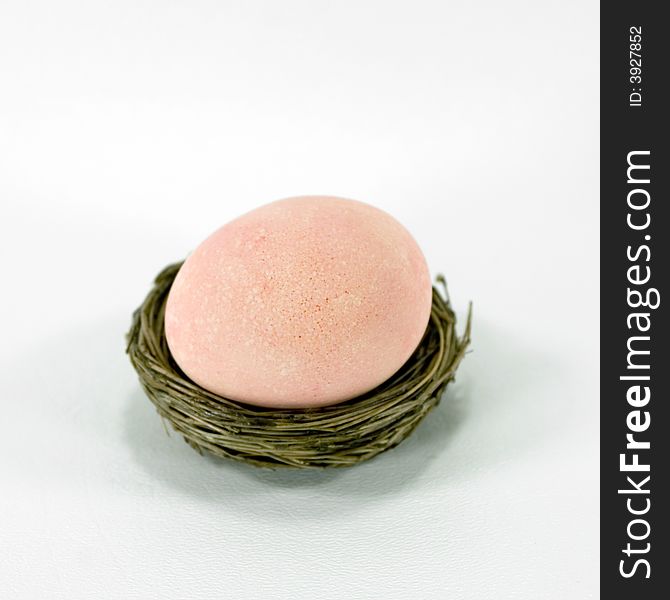 Light peach / orange / pink Easter egg in a nest. Light peach / orange / pink Easter egg in a nest