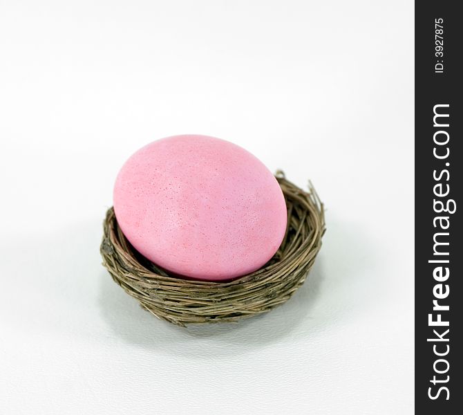 Pastel pink Easter egg in a nest.