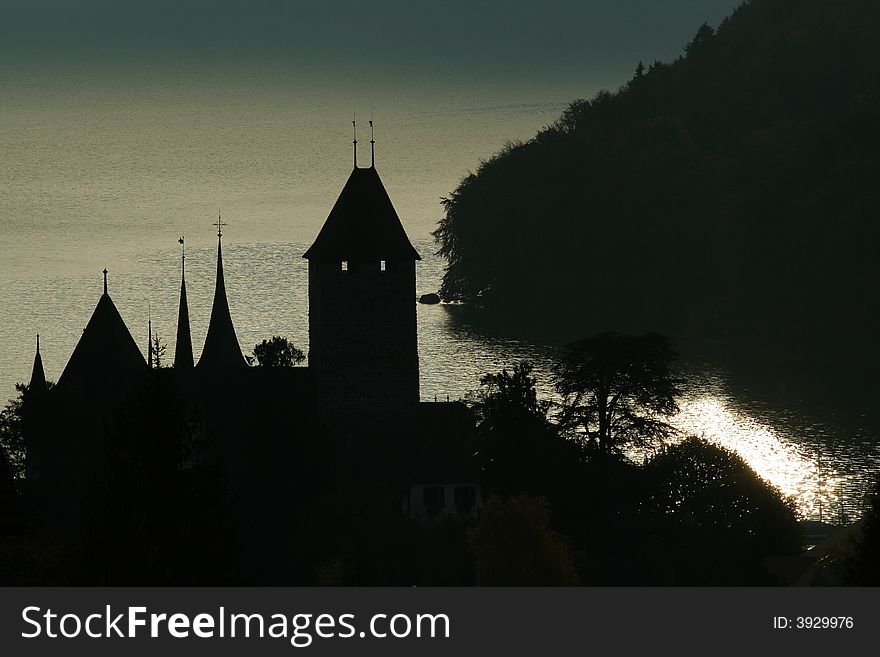 A castle tower silhouetted against a shimmering lake in the early morning. A castle tower silhouetted against a shimmering lake in the early morning
