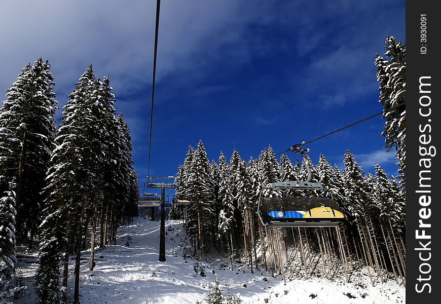 Ski lift with snowy trees and blue sky.