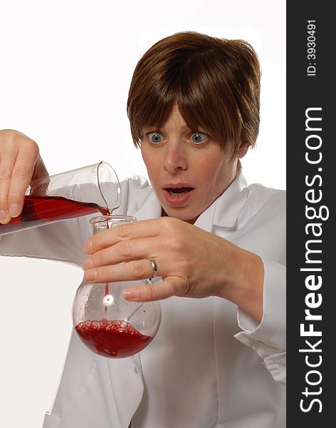 Worried young lady scientist in white coat, pouring liquid, isolated on white - humorous concept. Worried young lady scientist in white coat, pouring liquid, isolated on white - humorous concept