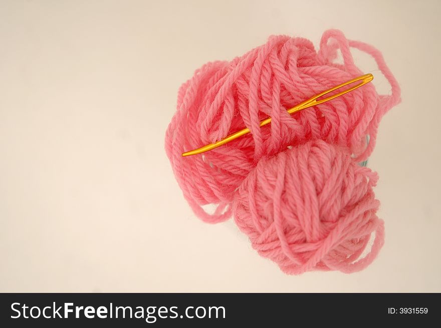 Pink yarn and gold darning needle isolated on white background
