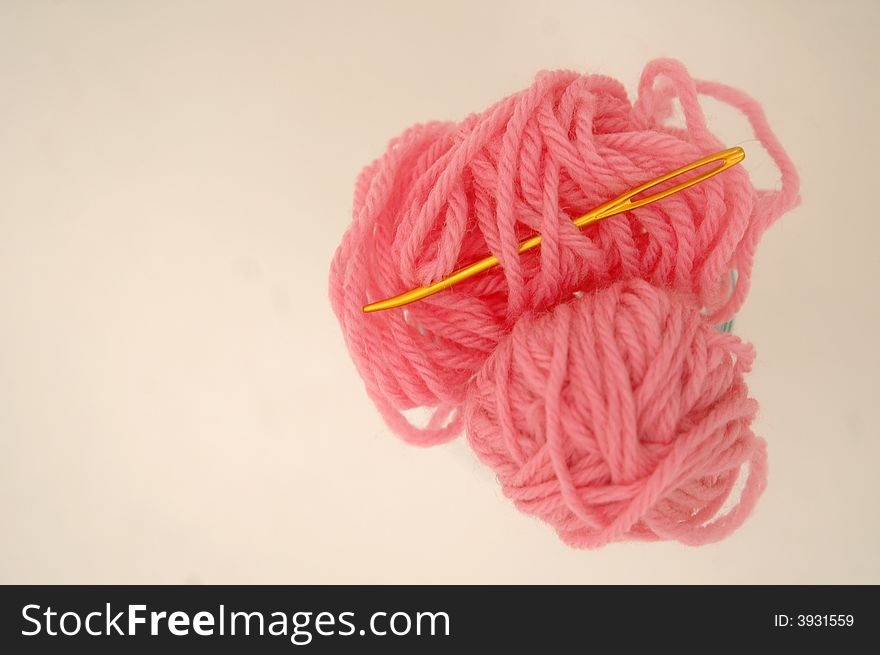 Pink yarn and gold darning needle