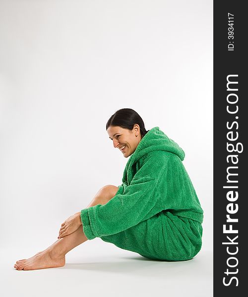 Sitting smiling woman in green bathrobe on white background. Sitting smiling woman in green bathrobe on white background