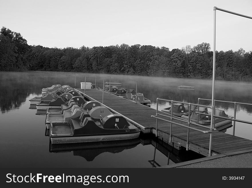 Paddle boats docked on misty lake black and white. Paddle boats docked on misty lake black and white