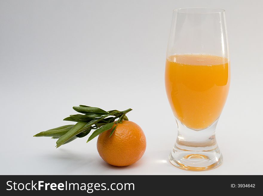 A glass of tanderine juice and fruit on white background