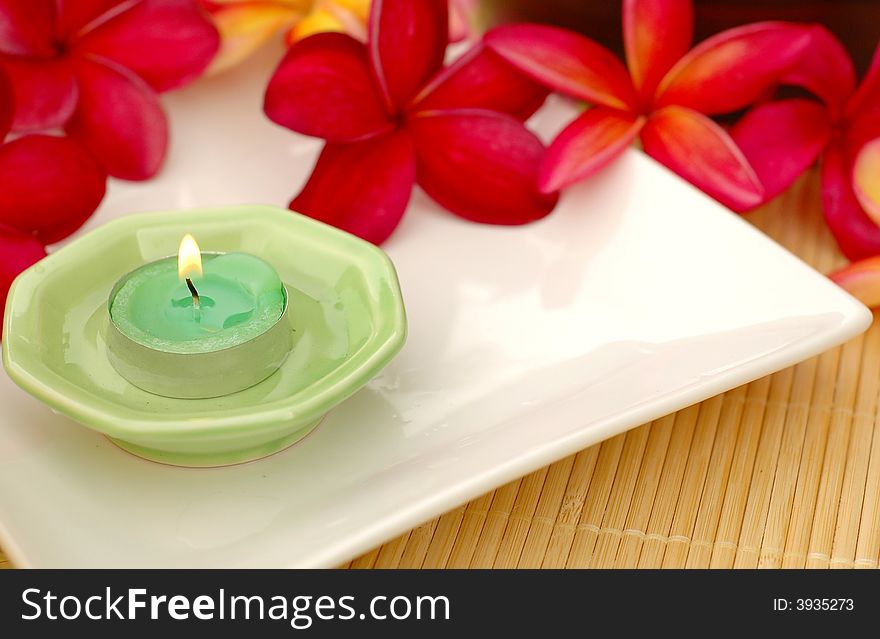 Aromatic candle and tropical red frangipanis. Aromatic candle and tropical red frangipanis