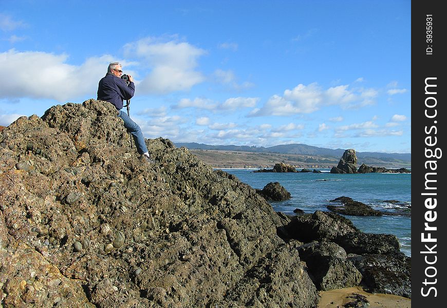 Photographer sitting on a rock on the shore waiting for the light