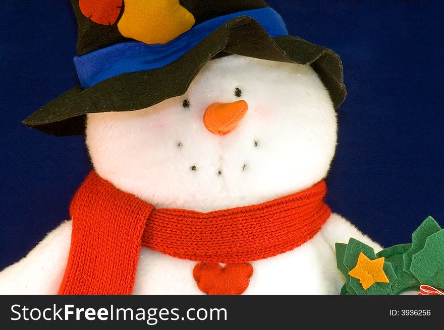 A colorfully stuffed toy snowman isolated on a dark blue background. A colorfully stuffed toy snowman isolated on a dark blue background.