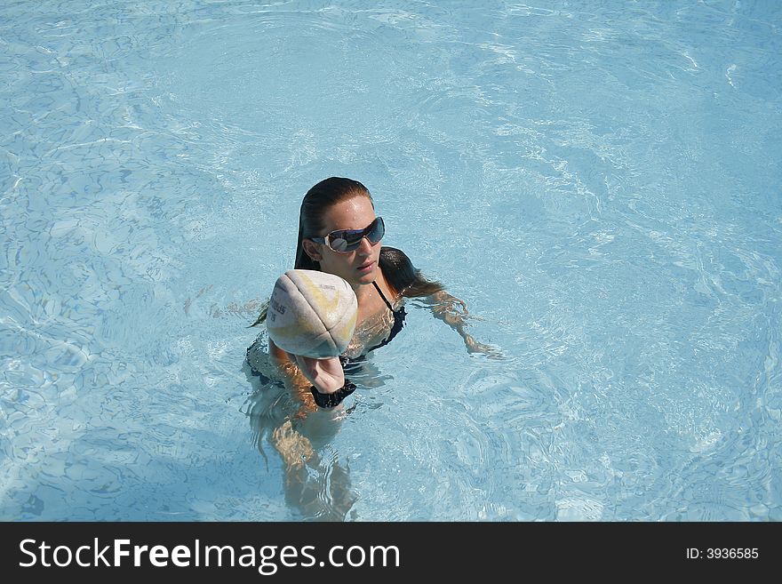 Young caucasian woman playing a game in the pool with her friends. Young caucasian woman playing a game in the pool with her friends