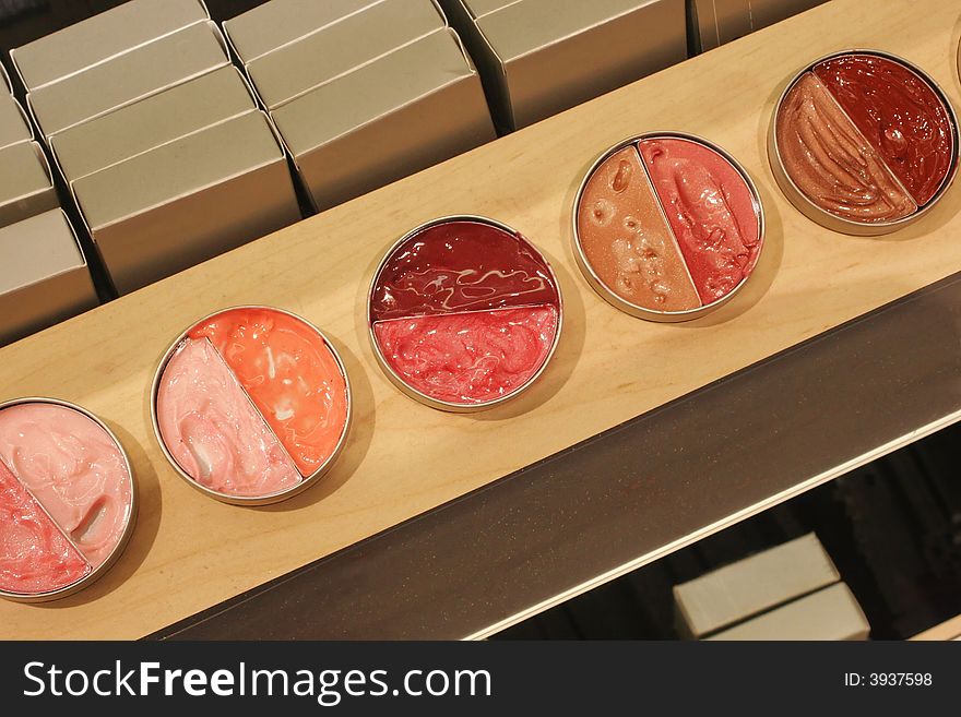 Colorful pots of lip gloss on wood display shelf.